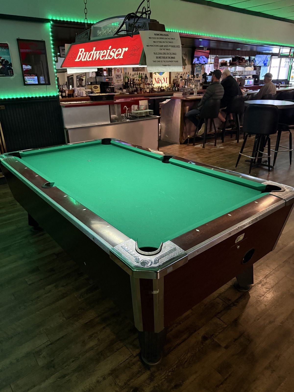 A pool table next to the bar at M&M